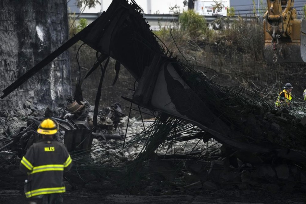 FILE - A firefighter views the aftermath of an elevated section of Interstate 95 that collapsed, in Philadelphia, Monday, June 12, 2023. A report released on June 11, 2024, says the gasoline delivery truck that destroyed the I-95 bridge a year ago says gasoline spilled out from an unsecured hatch on the top of the tanker. (AP Photo/Matt Rourke, File)