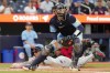 Cleveland Guardians' Brayan Rocchio (4) slides into home safely as Toronto Blue Jays catcher Danny Jansen (9) plays the ball during fifth inning MLB baseball action in Toronto on Friday, June 14, 2024. THE CANADIAN PRESS/Chris Young