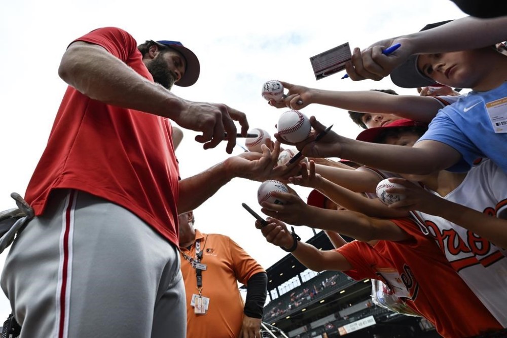 Philadelphia Phillies' Bryce Harper, left, gives autographs to young fans before a baseball game against the Baltimore Orioles, Friday, June 14, 2024, in Baltimore. (AP Photo/Terrance Williams)