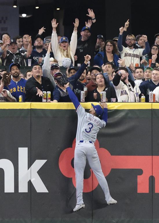 Texas Rangers outfielder Leody Taveras is unable to catch a two-run home run by Seattle Mariners' Mitch Garver during the first inning of a baseball game Friday, June 14, 2024, in Seattle. (AP Photo/Jason Redmond)
