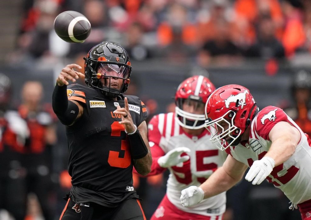 B.C. Lions quarterback Vernon Adams Jr., left, passes while being pursued by Calgary Stampeders' Micah Teitz during the first half of a CFL football game, in Vancouver, on Saturday, June 15, 2024. THE CANADIAN PRESS/Darryl Dyck