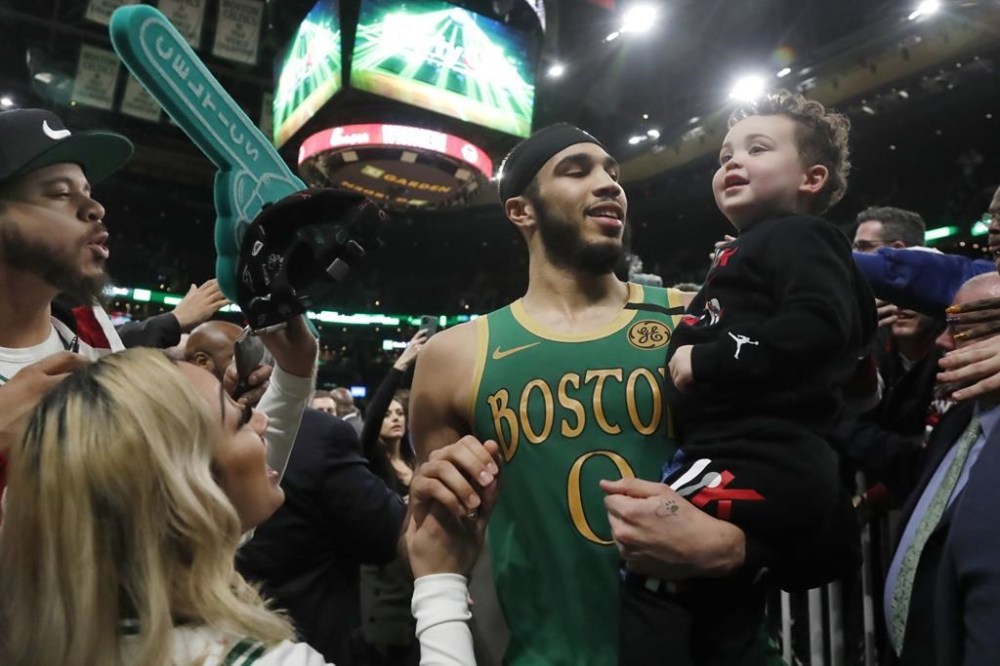 FILE - Fans reach out to Boston Celtics forward Jayson Tatum (0) as he leaves the court holding his son, Deuce, after the Celtics defeated the Los Angeles Clippers in a double overtime NBA basketball game, Feb. 13, 2020, in Boston. Tatum spent part of his Father’s Day, Sunday, June 16, 2024, thinking about how his son made him a better person — and probably a better basketball player, too. (AP Photo/Elise Amendola, File)