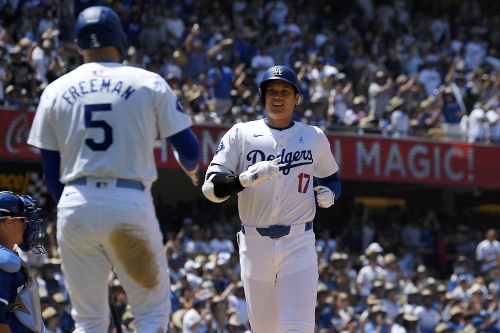 Los Angeles Dodgers' Shohei Ohtani, right, is congratulated by Freddie Freeman after hitting a solo home run during the sixth inning of a baseball game against the Kansas City Royals Sunday, June 16, 2024, in Los Angeles. (AP Photo/Mark J. Terrill)