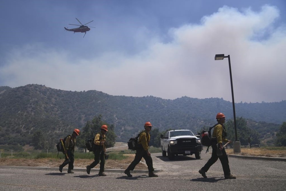 Fire crews walk along a road while fighting the Post Fire, Sunday, June 16, 2024, in Lebec, Calif. (AP Photo/Eric Thayer)