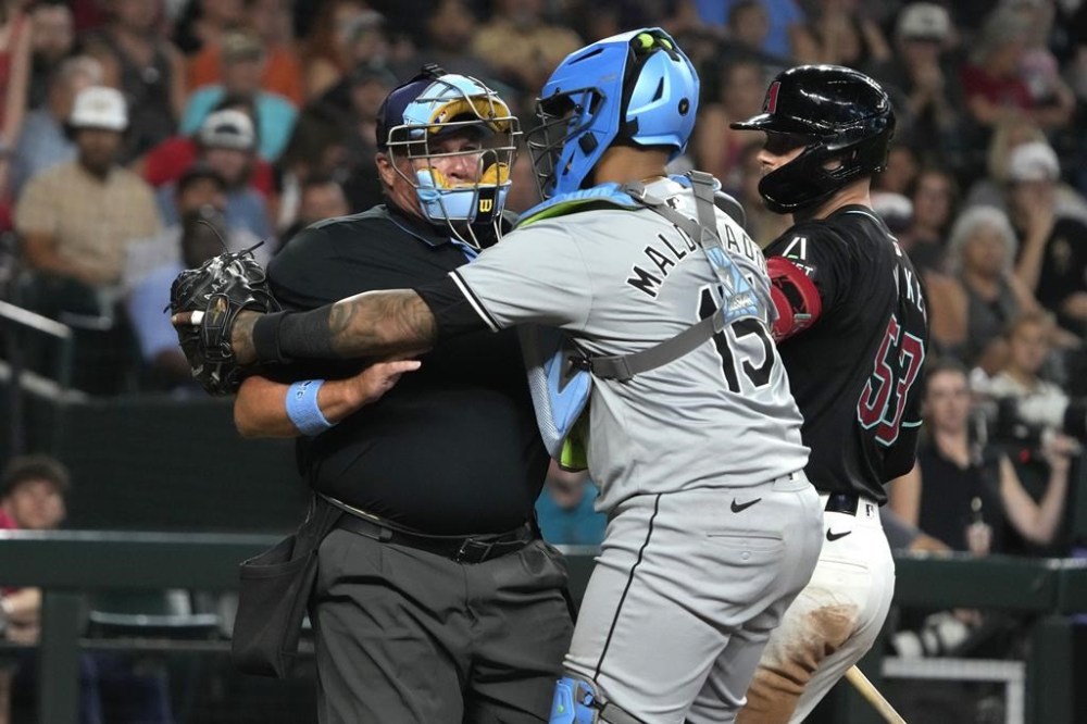 Chicago White Sox catcher Martin Maldonado (15) holds onto MLB umpire Marvin Hudson, left, after Hudson was hit with a foul ball in the sixth inning during a baseball game against the Chicago White Sox, Sunday, June 16, 2024, in Phoenix. Hudson left the game and did not return. (AP Photo/Rick Scuteri)