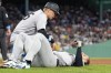 New York Yankees first base coach Travis Chapman, left, tends to Anthony Rizzo, right, following a first base collision in the seventh inning of a baseball game against the Boston Red Sox, Sunday, June 16, 2024, in Boston. Rizzo left the game after colliding with Red Sox pitcher Brennan Bernardino on a play at first and falling hard on his right wrist. (AP Photo/Steven Senne)