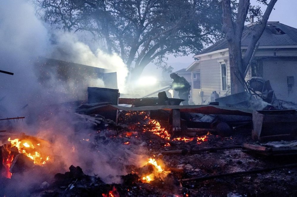 A firefighter sprays water on a burning outbuilding as the Point Fire spreads along West Dry Creek Road in Healdsburg, Calif., on Sunday, June 16, 2024. (AP Photo/Noah Berger)