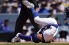 Los Angeles Dodgers' Mookie Betts, left, writhes on the ground after being hit by a pitch during the seventh inning of a baseball game against the Kansas City Royals Sunday, June 16, 2024, in Los Angeles. (AP Photo/Mark J. Terrill)