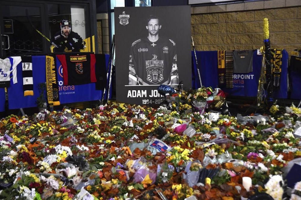 FILE - Flower tributes for Nottingham Panthers player Adam Johnson, who died last year from a skate cut to the neck, rest outside the Motorpoint Arena before a memorial ice hockey game between the Panthers and the Manchester Storm in Nottingham, England, Nov. 18, 2023. A Minnesota youth hockey camp is honoring the life of late alum Johnson with a scholarship in his honor. (AP Photo/Rui Vieira, File)
