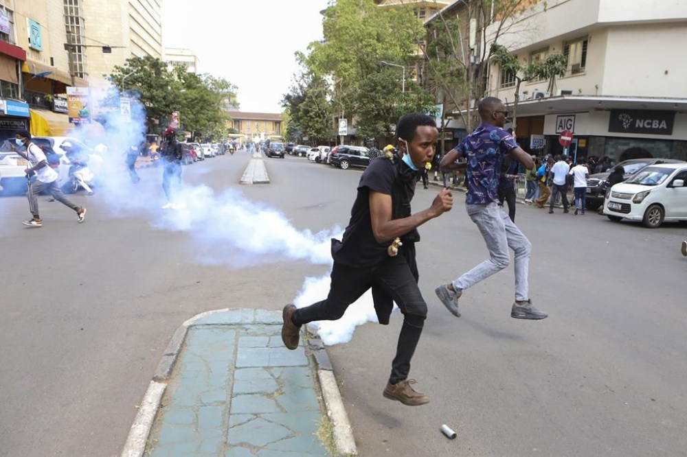 Demonstrators run from tear gas as they protest against proposed tax hikes in a finance bill that is due to be tabled in parliament in Nairobi, Kenya, Tuesday, June 18, 2024. Civil society groups say that despite the dozens of arrests, demonstrations and a planned sit-down outside the parliament buildings will continue. (AP Photo/Andrew Kasuku)