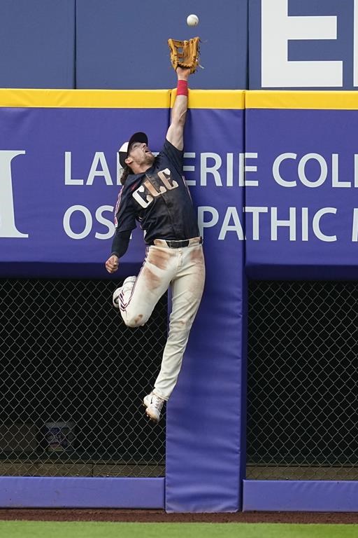 Cleveland Guardians center fielder Daniel Schneemann jumps for but can't catch the ball on a home run by Seattle Mariners' J.P. Crawford during the third inning of a baseball game Tuesday, June 18, 2024, in Cleveland. (AP Photo/Sue Ogrocki)