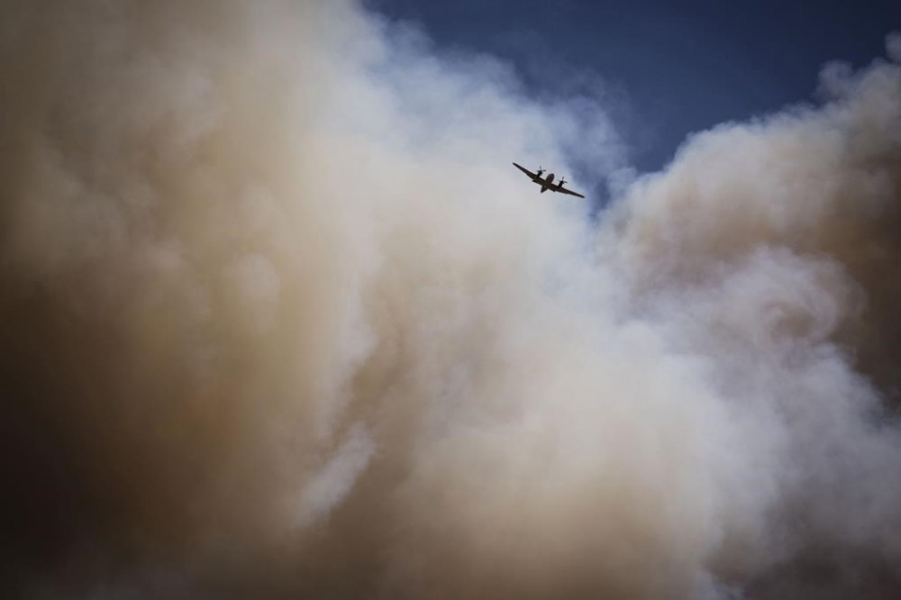 An air tanker soars through a large plume of smoke over and around wildfire-affected areas in the village of Ruidoso, N.M., Tuesday, June 18, 2024. (Chancey Bush/The Albuquerque Journal via AP)
