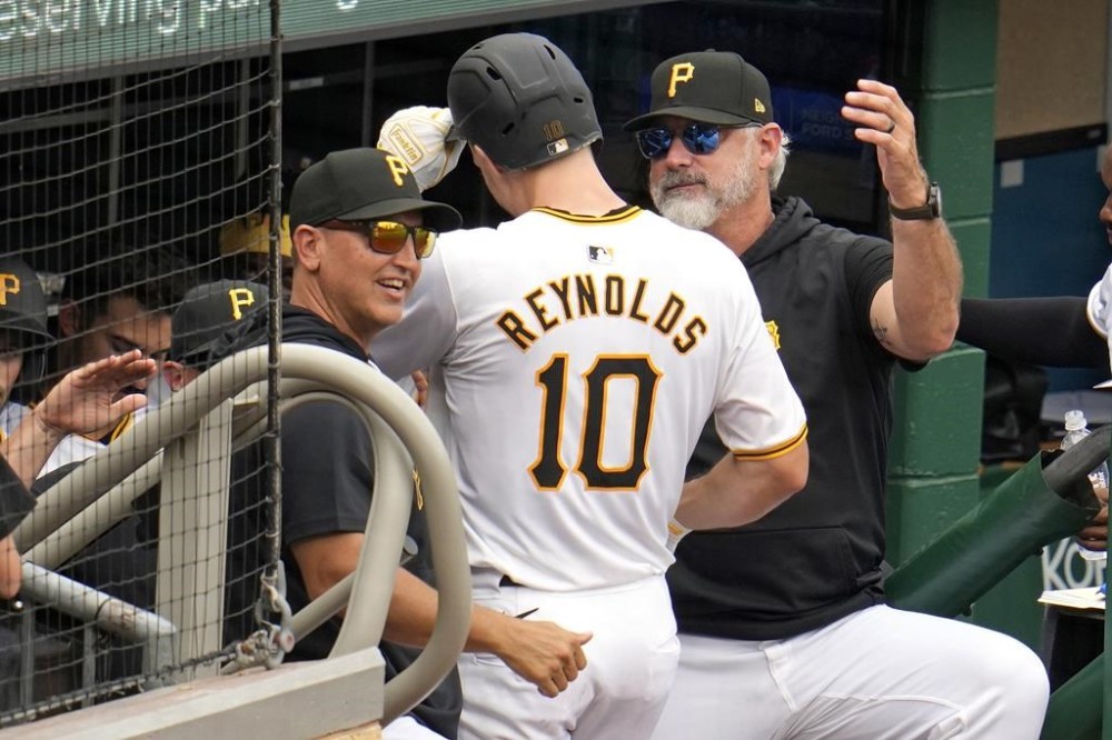Pittsburgh Pirates' Bryan Reynolds (10) is welcomed on the dugout steps by manager Derek Shelton, right, and hitting coach Andy Haines, left, after hitting a solo home run off Cincinnati Reds relief pitcher Nick Martinez during the eighth inning of a baseball game in Pittsburgh, Wednesday, June 19, 2024. The Pirates won 1-0. (AP Photo/Gene J. Puskar)