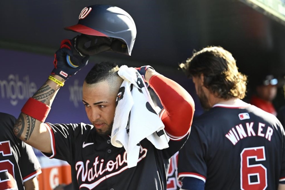 Washington Nationals Eddie Rosario, left, wipes the perspiration off his head in the dugout during the eighth inning of a baseball game against the Arizona Diamondbacks Wednesday, June 19, 2024, in Washington. (AP Photo/John McDonnell)