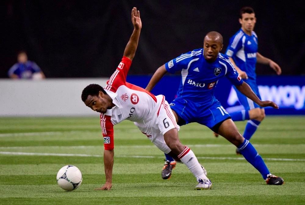 Toronto FC's Julian de Guzman slips as he goes for the ball ahead of Montreal Impact's Collen Warner during second half of Amway Canadian Championship, Wednesday, May 2, 2012 in Montreal. Toronto FC will find a familiar face rooting against them Saturday at Red Bull Arena. THE CANADIAN PRESS/Paul Chiasson