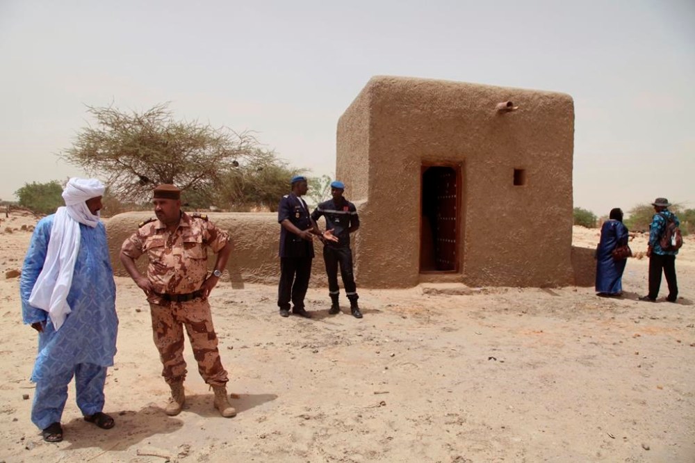 FILE - People attending a ceremony stand near a mausoleum, right, that was restored in Timbuktu, Mali, July 18, 2015, after the 14 mausoleums in Mali's northern historic city that had been destroyed by Islamic extremists in 2012 have been restored. The International Criminal Court unsealed an arrest warrant Friday June 21, 2024, for a Malian accused of war crimes and crimes against humanity in the desert city of Timbuktu in 2012-13, where he is suspected of leading an al-Qaida-linked Islamic extremist group. (AP Photo/Baba Ahmed, File)