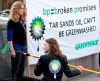 Greenpeace activists, some dressed in business suits and wearing smoke stack hats, 'greenwash' BP's Calgary headquarters with large letters spelling out 'TAR SANDS' in Calgary, Thursday, April 15, 2010. THE CANADIAN PRESS/Jeff McIntosh
