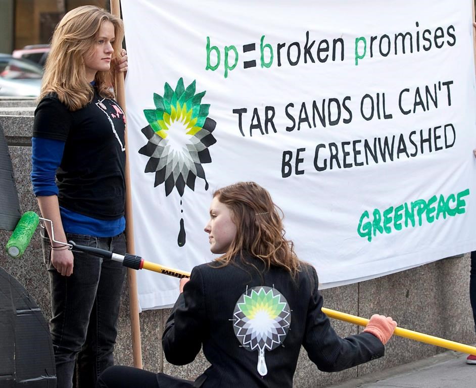 Greenpeace activists, some dressed in business suits and wearing smoke stack hats, 'greenwash' BP's Calgary headquarters with large letters spelling out 'TAR SANDS' in Calgary, Thursday, April 15, 2010. THE CANADIAN PRESS/Jeff McIntosh
