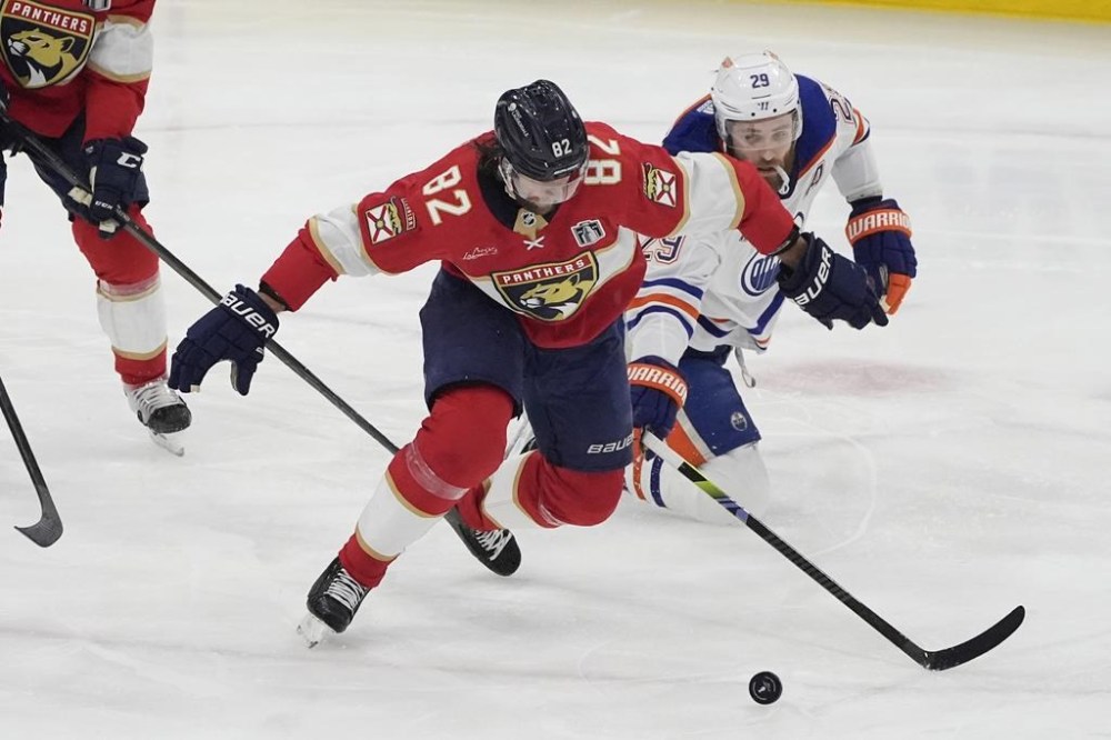 Edmonton Oilers center Leon Draisaitl (29) and Florida Panthers center Kevin Stenlund (82) go after the puck during the second period of Game 7 of the NHL hockey Stanley Cup Final, Monday, June 24, 2024, in Sunrise, Fla. (AP Photo/Rebecca Blackwell)