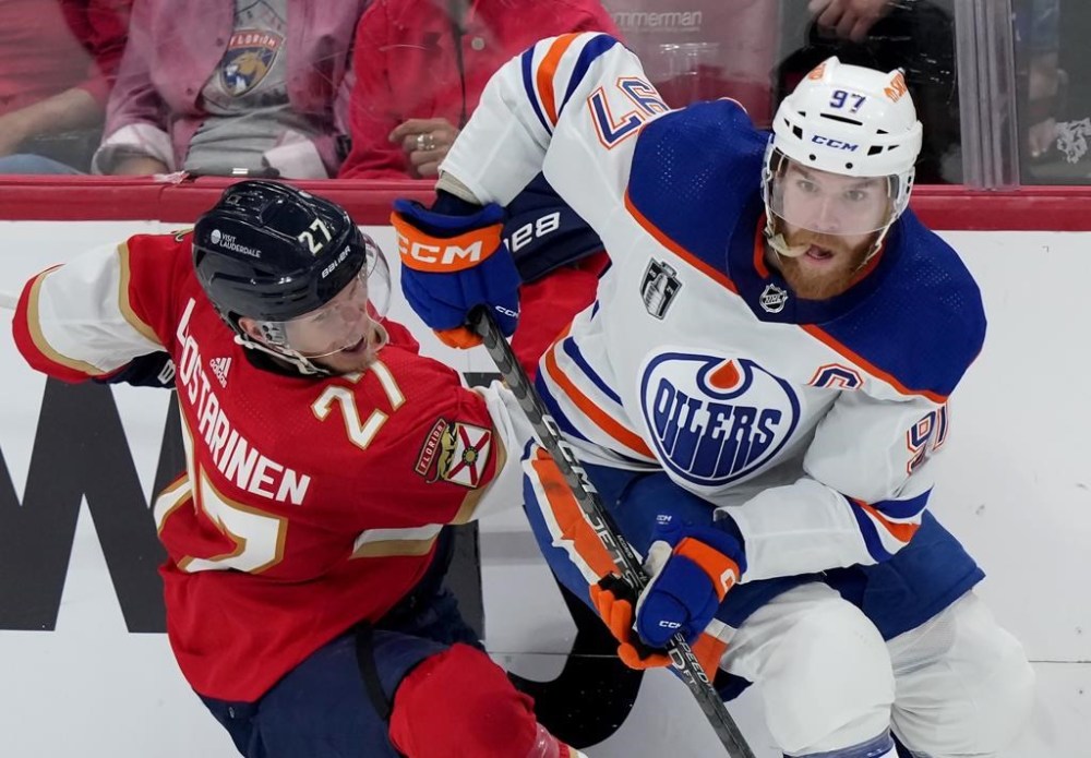 Edmonton Oilers forward Connor McDavid (97) dumps Florida Panthers forward Eetu Luostarinen (27) against the boards as he turns with the puck during second period game 7 of the NHL Stanley Cup finals in Sunrise, Fla., on Monday, June 24, 2024. THE CANADIAN PRESS/Nathan Denette