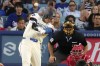 Los Angeles Dodgers' Shohei Ohtani, left, hits a two-run home run as Los Angeles Angels catcher Logan O'Hoppe, right, watches along with home plate umpire James Hoye during the third inning of a baseball game Saturday, June 22, 2024, in Los Angeles. (AP Photo/Mark J. Terrill)