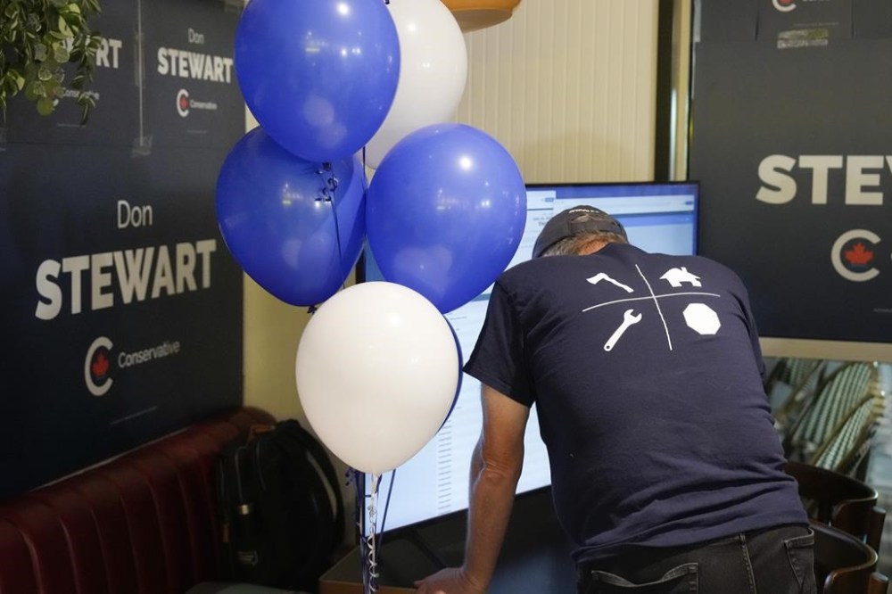 A Conservative supporters watches a split screen displaying voting results and the Stanley Cup final, at an Federal byelection election night event for Toronto-St.Paul's candidate Don Stewart in Toronto on Monday, June 24, 2024.THE CANADIAN PRESS/Chris Young