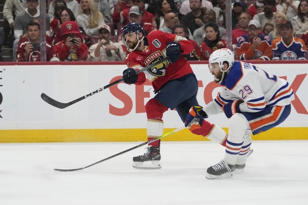 Florida Panthers center Sam Reinhart, left, aims the puck for a goal as Edmonton Oilers center Leon Draisaitl (29) attempts to defend during the second period of Game 7 of the NHL hockey Stanley Cup Final, Monday, June 24, 2024, in Sunrise, Fla. (AP Photo/Wilfredo Lee)