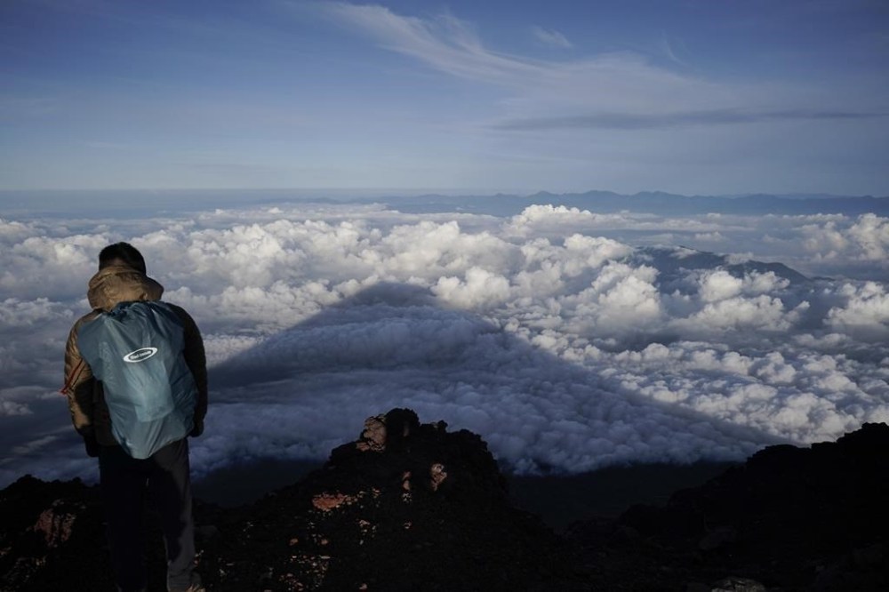 FILE - The shadow of Mount Fuji is cast on clouds hanging below the summit Aug. 27, 2019, in Japan. Three bodies were found inside a crater at the summit of Mount Fuji, Japan’s most famous mountain, with one of them already brought down from the slopes, police said Thursday, June 27, 2024. (AP Photo/Jae C. Hong, File)