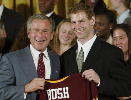 FILE - President Bush, left, holds up a jersey presented to him by Grant Potulny, right, captain of the University of Minnesota men's ice hockey, as the 2003 NCAA champions were honored in the East Room of the White House in Washington, June 17, 2003. Potulny is leaving Northern Michigan to become the coach of the New York Rangers' American Hockey League affiliate in Hartford, Connecticut. Rangers president and general manager Chris Drury announced the hiring of the 44-year-old Potulny on Thursday, June 27, 2024.(AP Photo/Pablo Martinez Monsivais, File)