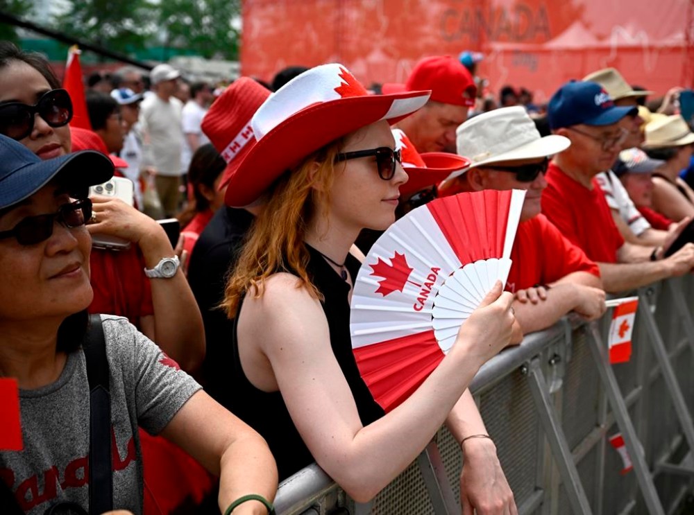A person cools themselves with a fan during the Canada Day noon show in Ottawa on Saturday, July 1, 2023. THE CANADIAN PRESS/Justin Tang