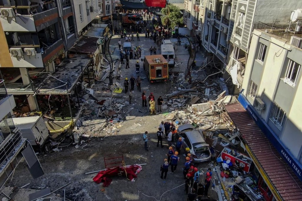 Firefighters and emergency team members work during the aftermath of an explosion in a restaurant in Izmir, western Turkey, Sunday, June 30, 2024. Turkish authorities say a propane tank explosion at a restaurant in the western city of Izmir has left at least five people dead and over 60 others injured. Security cameras recorded the explosion on Sunday that devastated the street and caused minor damage to surrounding buildings. (Mustafa Ic/IHA via AP)