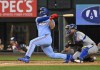Texas Rangers' Wyatt Langford, left, hits an RBI double in the fifth inning as Kansas City Royals catcher Salvador Perez, right, looks on in a baseball game Sunday, June 23, 2024, in Arlington, Texas. (AP Photo/Albert Pena)