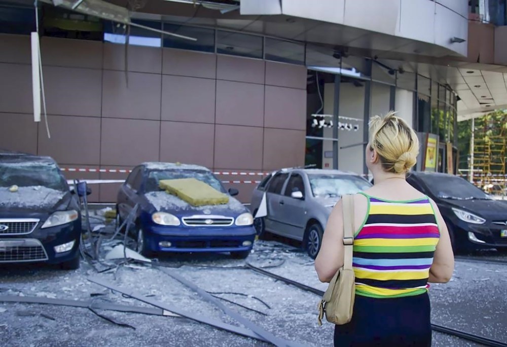 In this photo released by the Dnipro Regional Administration, a woman looks on damaged cars after Russia's missile attack in Dnipro, Ukraine, Wednesday, July 3, 2024. (Dnipro Regional Administration via AP)