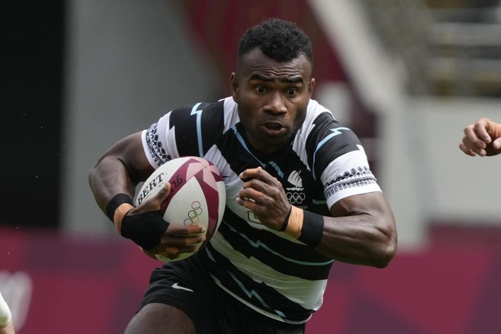 FILE - Fiji's Jerry Tuwai, center, evades Britain's Alex Davis as Fiji's Meli Derenalagi looks on, in their men's rugby sevens match at the 2020 Summer Olympics, on July 27, 2021 in Tokyo, Japan. Osea Kolinisau led Fiji to its first ever Olympic gold medal when rugby sevens made its debut at the Summer Games in 2016 and now, as a coach, he’s turning to old teammate Jerry Tuwai to help the Pacific nation’s bid for a three-peat. (AP Photo/Shuji Kajiyama, File)