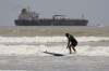 An oil taker heads out to open water as a surfer takes advantage of waves ahead of Hurricane Beryl's arrival in Port Aransas, Texas, Saturday, July 6, 2024. (AP Photo/Eric Gay)