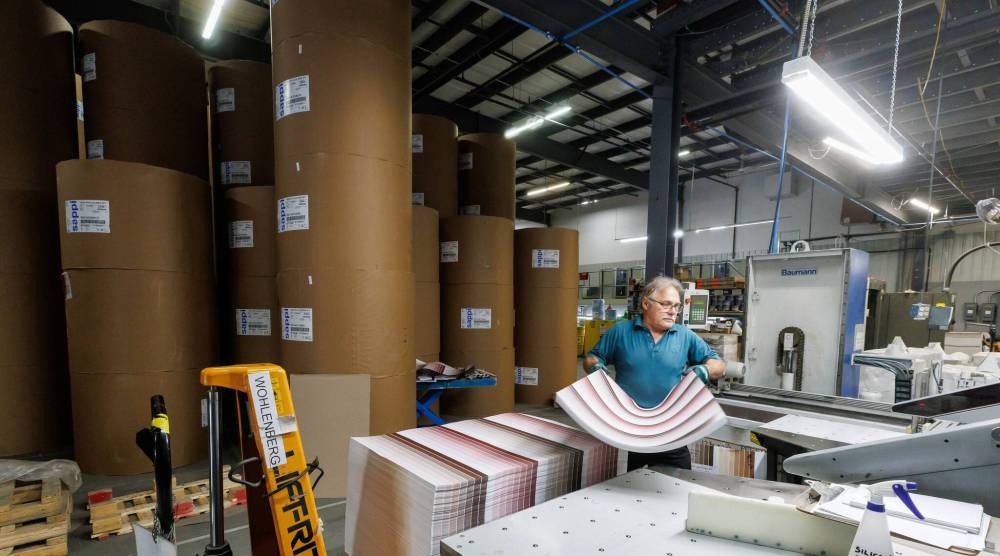 MIKE DEAL / FREE PRESS
Amid the work stations on the plant floor, Jack Sitar operates a squaring cutter while giant rolls of paper wait for the printing press.