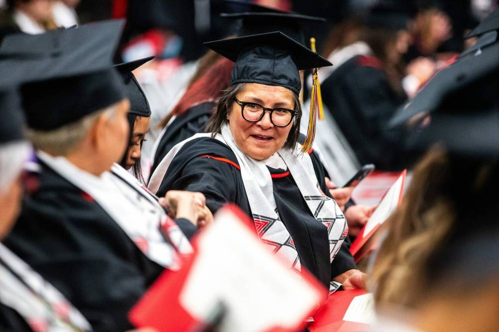 MIKAELA MACKENZIE / FREE PRESS
                                U of W’s Developmental Studies program graduate Liz Keeper-Garson reaches across to shake hands with fellow graduates after crossing the stage on Friday.