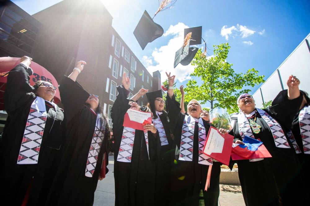 MIKAELA MACKENZIE / FREE PRESS
                                U of W’s Developmental Studies program graduates throw their caps for a group photo after their graduation ceremony.