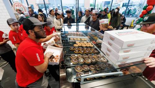 Lovers of fried pastries endured long lines and rainy conditions to be some of the first to purchase Krispy Kreme doughnuts during its grand opening early Tuesday. (Mike Deal / Free Press)
