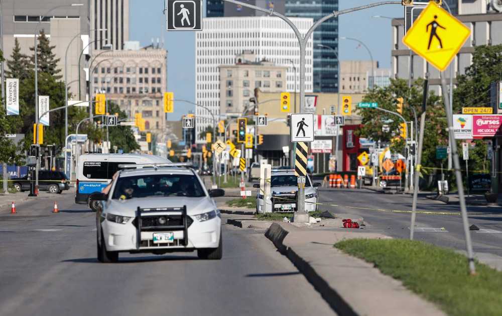 JOHN WOODS / FREE PRESS
Police investigate at the scene of a reported shooting at a crosswalk on Notre Dame Avenue on Tuesday.