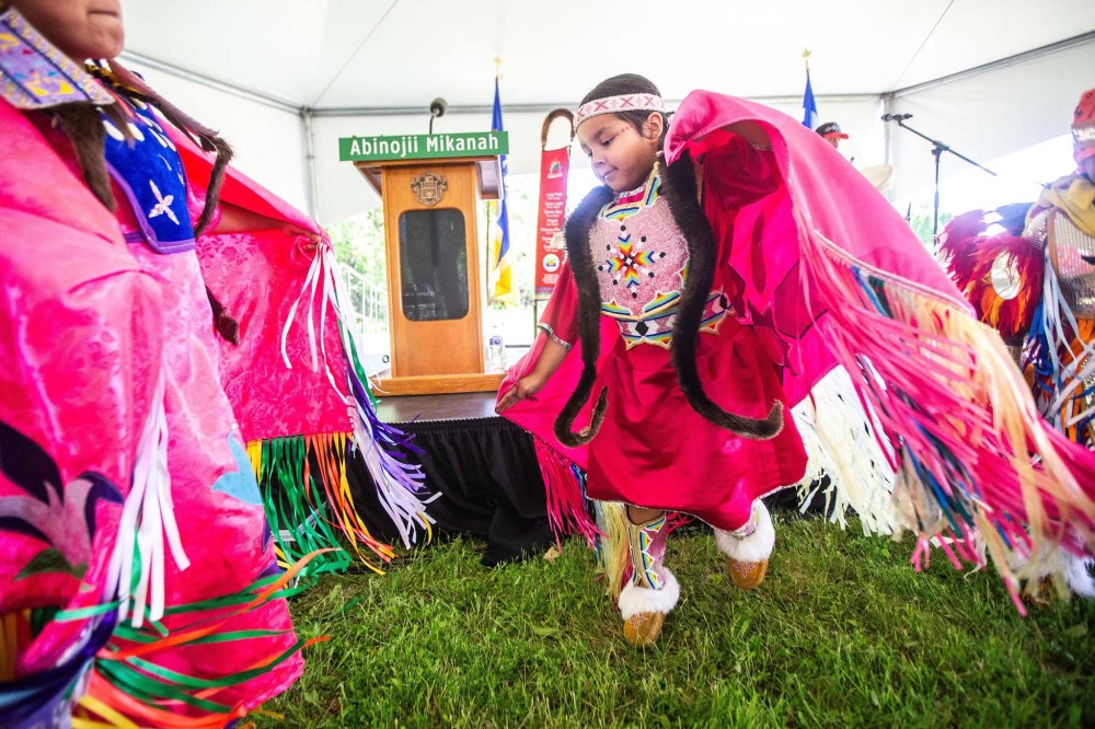 Callie Thompson (nine, left) and Aubree Kakewash (six) dance fancy shawl at the Abinojii Mikanah renaming ceremony on Friday. (Mikaela MacKenzie / Free Press)
