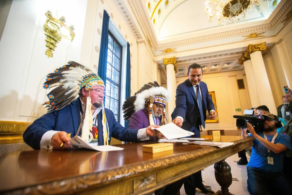 MIKAELA MACKENZIE / FREE PRESS Minegoziibe Anishinaabe chief Derek Nepinak (left), Wuskwi Sipihk First Nation chief Elwood Zastre, and premier Wab Kinew sign an agreement between three First Nations and the province of Manitoba at the Manitoba Legislative Building on Friday, June 28, 2024. For Martin Cash story.