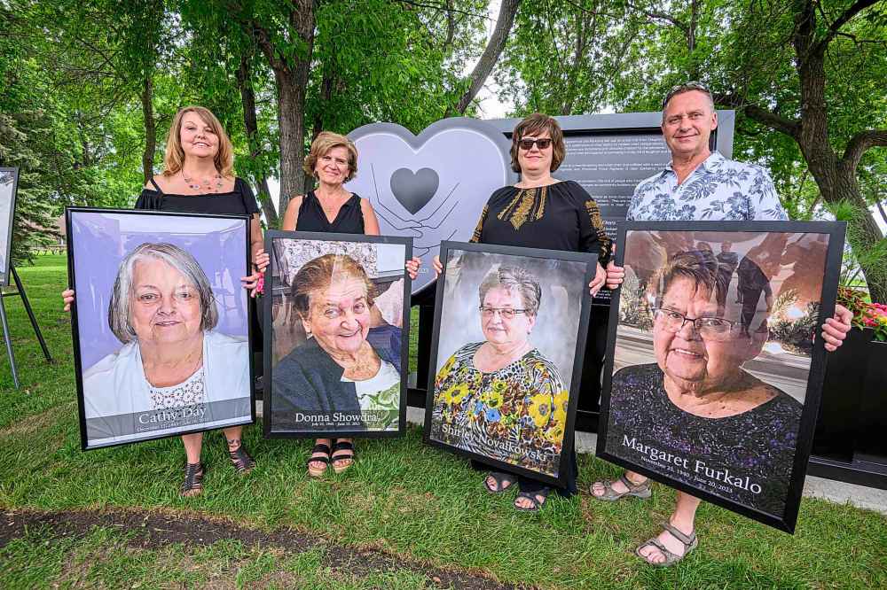 Teresa Rausch (from left) Darlene Prytula, Lavonne Tyscinski and Patrick Furkalo hold up framed photos of family members they lost. (Mike Sudoma / The Canadian Press)