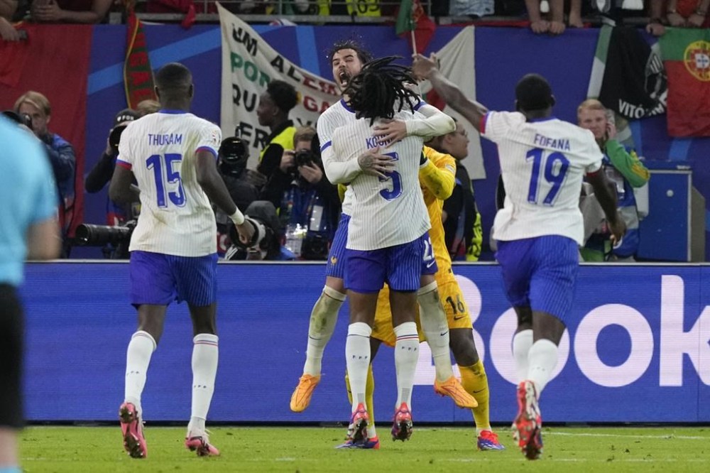 Theo Hernandez of France, top center, and Jules Kounde celebrate after Hernandez scored the deciding goal in a shootout to win a quarter final match between Portugal and France at the Euro 2024 soccer tournament in Hamburg, Germany, Friday, July 5, 2024. (AP Photo/Frank Augstein)