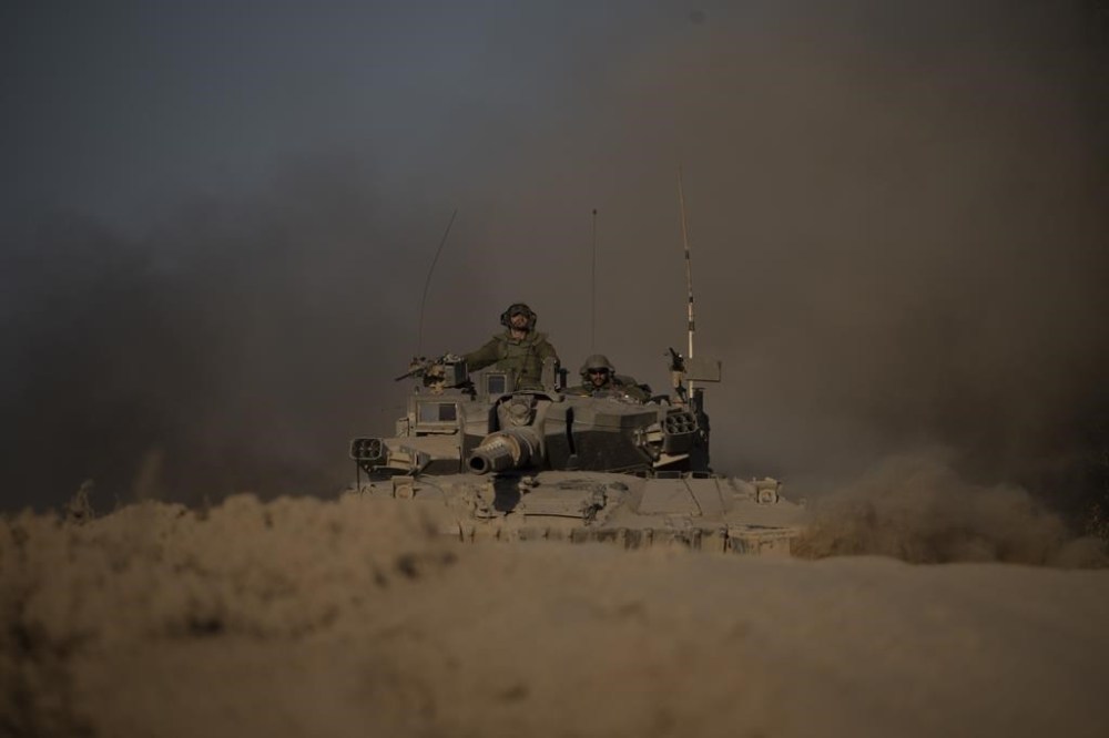 Israeli soldiers move on the top of a tank near the Israeli-Gaza border, as seen from southern Israel, Monday, July 8, 2024. Israeli forces advanced deeper into the Gaza Strip's largest city in pursuit of militants who had regrouped there, sending thousands of Palestinians fleeing on Monday from an area ravaged in the early weeks of the nine-month-long war. (AP Photo/Leo Correa)