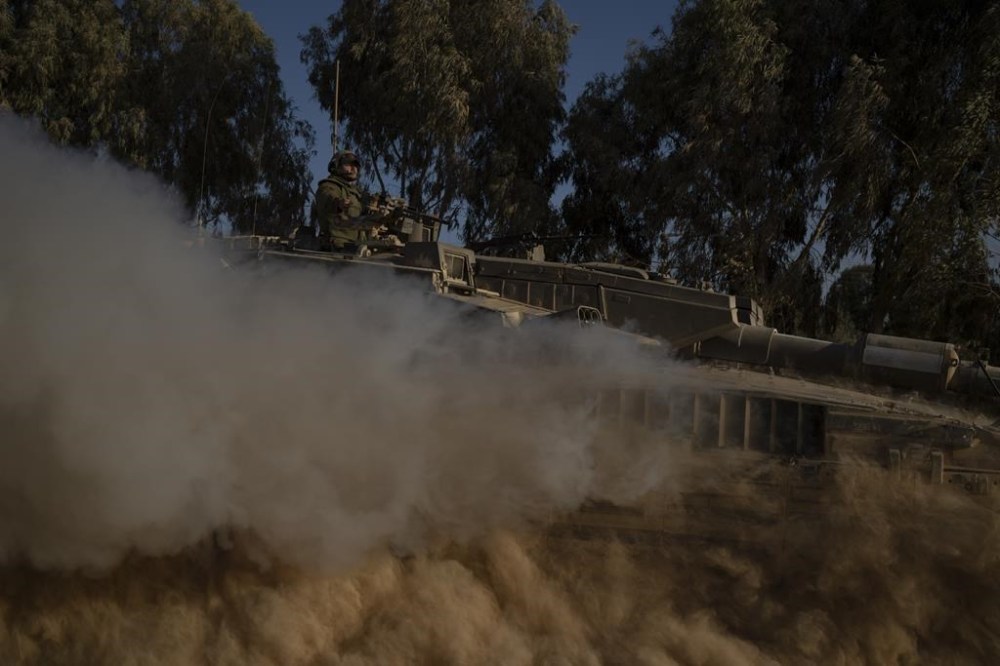 Israeli soldiers move on the top of a tank near the Israeli-Gaza border, as seen from southern Israel, Monday, July 8, 2024. Israeli forces advanced deeper into the Gaza Strip's largest city in pursuit of militants who had regrouped there, sending thousands of Palestinians fleeing on Monday from an area ravaged in the early weeks of the nine-month-long war. (AP Photo/Leo Correa)