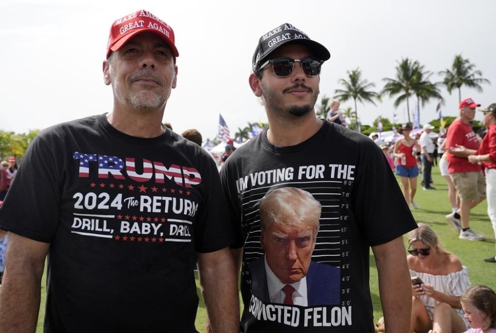 Hector Grass and his son Hector Jr. of Miami, watch a video before Republican presidential candidate former President Donald Trump speaks at a campaign rally at Trump National Doral Miami, Tuesday, July 9, 2024, in Doral, Fla. (AP Photo/Marta Lavandier)