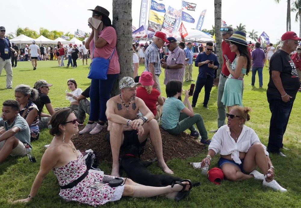 Supporters take shelter under a palm tree as they wait for Republican presidential candidate former President Donald Trump to speak at a campaign rally at Trump National Doral Miami, Tuesday, July 9, 2024, in Doral, Fla. Miami-Dade County is under a heat advisory. (AP Photo/Marta Lavandier)