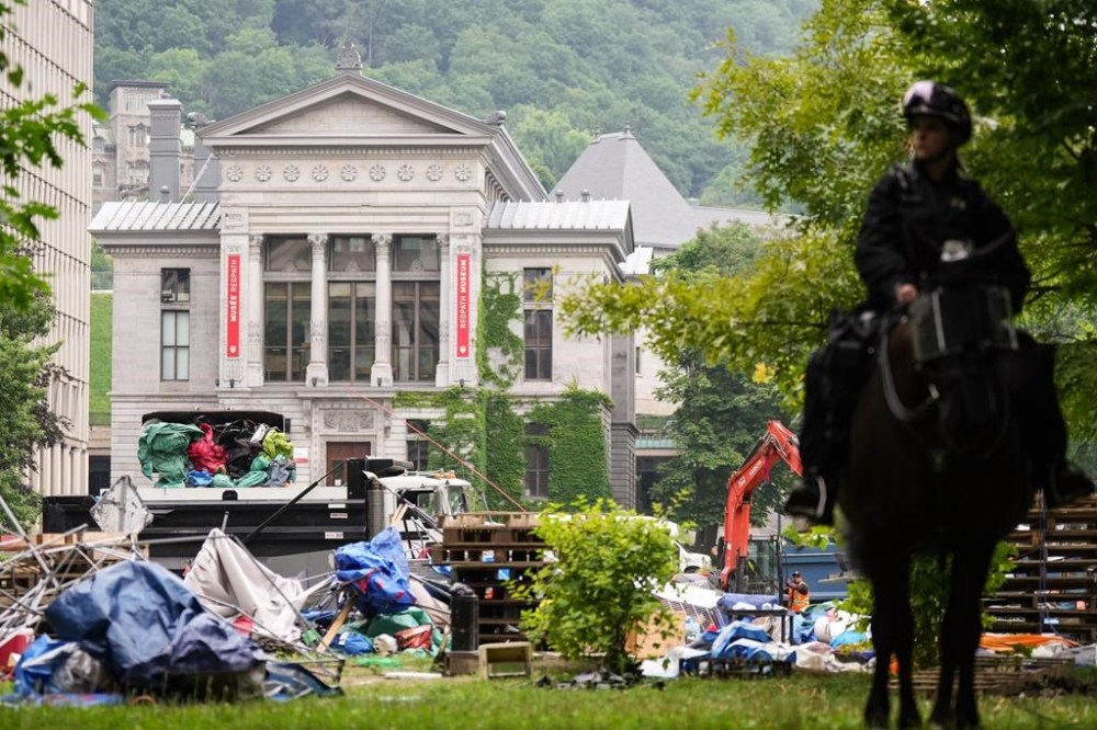 A backhoe dumps tenting into a dumpster as a pro-Palestinian encampment is dismantled at McGill University in Montreal, Wednesday, July 10, 2024. The encampment at McGill was the first of its kind in the country, and its dismantling this week has left activists and observers wondering what comes next for pro-Palestinian protests in Canada. THE CANADIAN PRESS/Christinne Muschi
