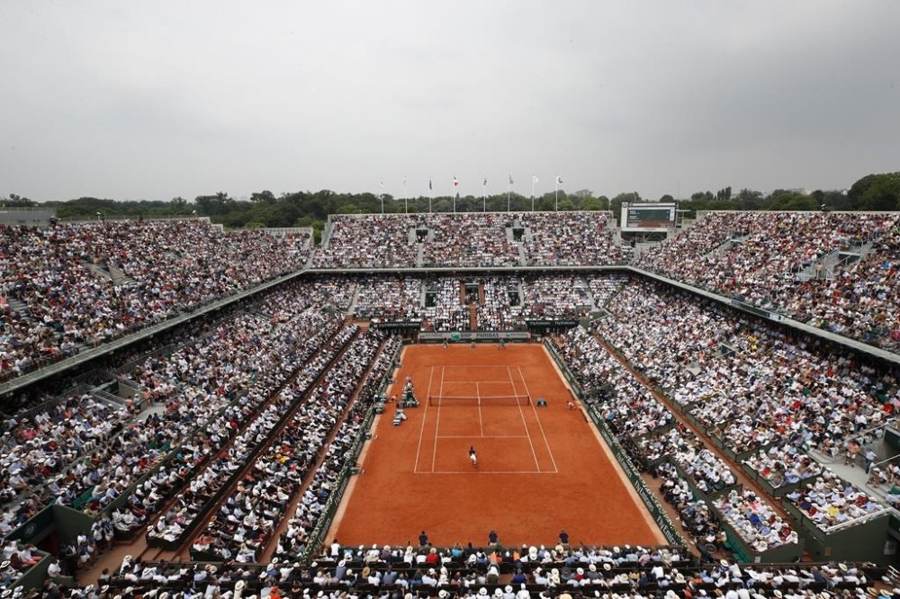 FILE - The crowd watch Austria's Dominic Thiem serving to Spain's Rafael Nadal during the men's final match of the French Open tennis tournament Roland Garros stadium in Paris, Sunday, June 10, 2018. The same courts used for the French Open each year — usually from late May to early June — will host tennis at these Olympics, so it's a surface and site familiar to the athletes, but they'll be making the unusual transition from the grass at Wimbledon to the clay at Roland Garros.(AP Photo/Christophe Ena)